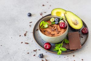 Raw,avocado,chocolate,mousse,topped,with,chocolate,pieces,,cherry,,blueberry