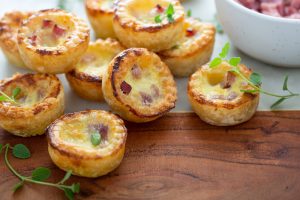 Mini,ham,and,cheese,quiches,freshly,baked,on,a,marble