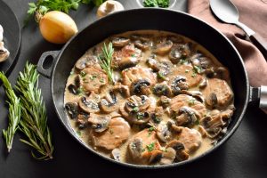 Pork,medallions,in,mushroom,gravy,in,cast,iron,pan,over